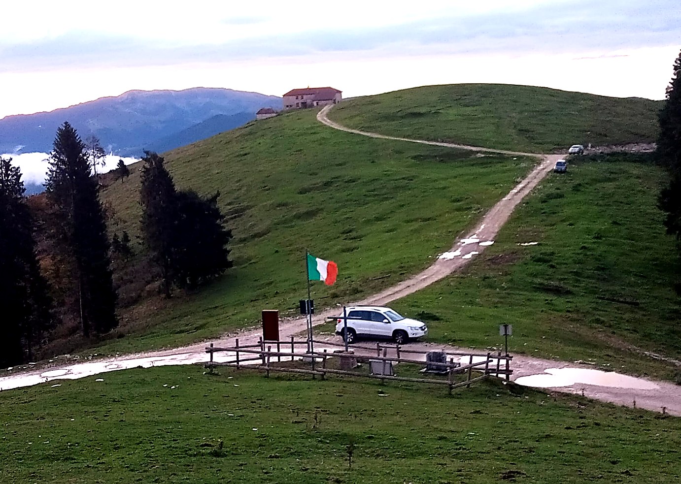 Il cippo del Capitano Bertolotti alla Selletta Baratono all'alba, con il tricolore issato e la malga sul crinale